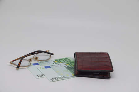 Brown wallet with banknotes and glasses. brown frame. Symbol of accounting and family finance planningの写真素材