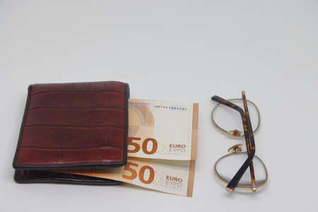 Brown wallet with banknotes and glasses. brown frame. Symbol of accounting and family finance planningの写真素材