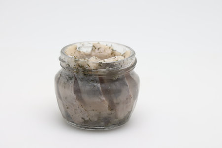 Pickled herring in a glass jar. Herring marinated with mustard, vinegar, onion, oil, dill and sour cream. Scandinavian cuisineの写真素材