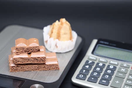 Sweet cakes and aerated chocolate on a dark background. unhealthy foods. The concept of a healthy lifestyle. diet violation. weight controlの写真素材
