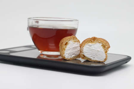 Small cakes with cream on kitchen electronic scales. Profiteroles. Diet and calorie counting. weight...