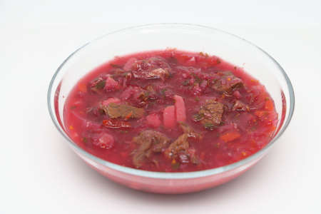 Red flavored fresh borscht soup in transparent brown tempered glass plate with handles, metal steel...