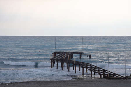 A lone figure in front of foam waves and a historic mountain in Alanya, November 2021の写真素材