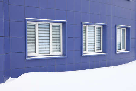 The wall of the house is covered with a large snowdrift for warmth. There is a small window and part of the roof. backgroundの写真素材