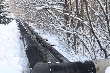 The main provides the city with hot water. selective focus. The large pipes of the central heating system are covered with snow. Icicles on pipes. fuel crisis. Increasing the cost of heatingの写真素材