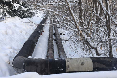 The main provides the city with hot water. selective focus. The large pipes of the central heating system are covered with snow. Icicles on pipes. fuel crisis. Increasing the cost of heatingの写真素材