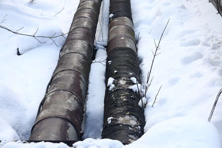 The main provides the city with hot water. selective focus. The large pipes of the central heating system are covered with snow. Icicles on pipes. fuel crisis. Increasing the cost of heatingの写真素材