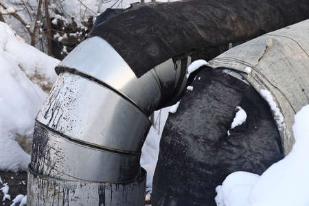 The main provides the city with hot water. selective focus. The large pipes of the central heating system are covered with snow. Icicles on pipes. fuel crisis. Increasing the cost of heatingの写真素材