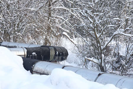 The main provides the city with hot water. selective focus. The large pipes of the central heating system are covered with snow. Icicles on pipes. fuel crisis. Increasing the cost of heatingの写真素材