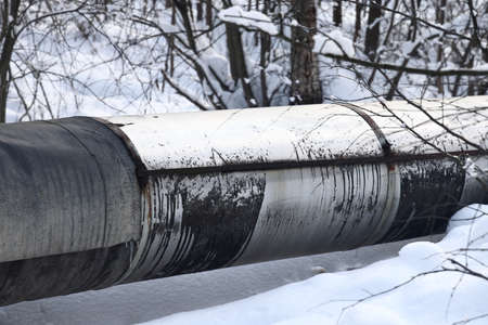 The main provides the city with hot water. selective focus. The large pipes of the central heating system are covered with snow. Icicles on pipes. fuel crisis. Increasing the cost of heatingの写真素材