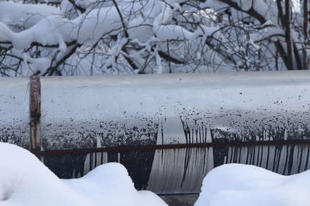 The main provides the city with hot water. selective focus. The large pipes of the central heating system are covered with snow. Icicles on pipes. fuel crisis. Increasing the cost of heatingの写真素材