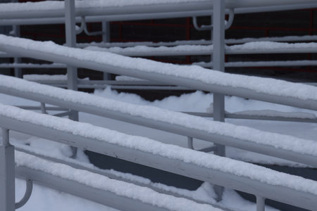 Snow stuck to the shiny light metal railing at the entrance of a residential building on a cold winter dayの写真素材