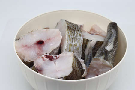 Pieces of fresh raw hake fish on white background
