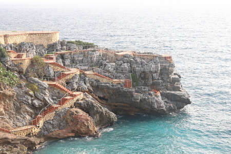 Staircase and cafe on a rock jutting out into the sea, surf and sheer cliffs, Antalya, Turkeyの写真素材