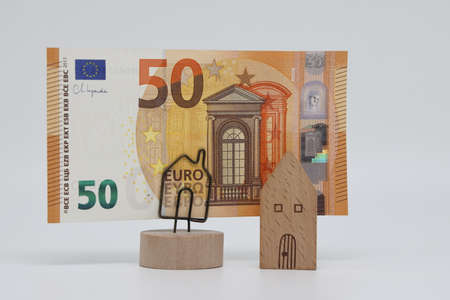The toy house stands next to the banknote on the stand. Accurate financial calculation when buying a propertyの写真素材