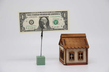 The toy house stands next to the banknote on the stand. Accurate financial calculation when buying a propertyの写真素材