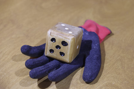 a wooden dice lies on a work glove, selective focus. unpredictabilityの写真素材