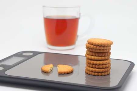 a cup of tea and cookies on a kitchen scale, food and drink, breakfast table, dessert table, calorie...