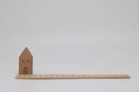 Wooden ruler and toy house lie next to banknotes, real estate appraisalの写真素材