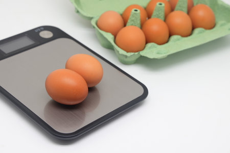 Eggs on a flat kitchen scale and in a carton, calorie counting, diet, practical nutritionの写真素材