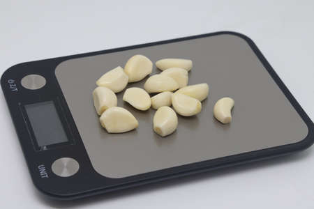 Peeled garlic cloves lie on an electronic kitchen scale, proper nutrition, calorie counting