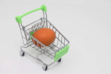 Raw egg in a grocery basket on a white background. Healthy breakfast ingredient. Diet and shopping in retail chainsの写真素材