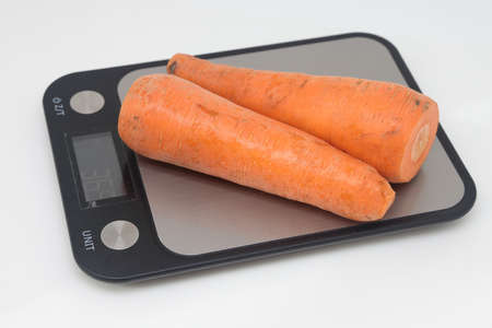 Poorly washed carrots lie on the kitchen electronic scales, carrots decay, calorie counting, proper nutritionの写真素材