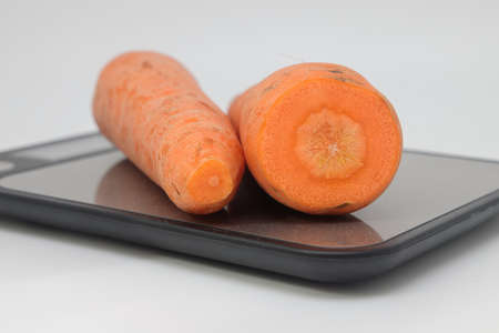 Poorly washed carrots lie on the kitchen electronic scales, carrots decay, calorie counting, proper nutritionの写真素材