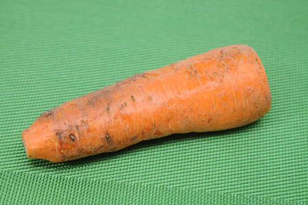 Poorly washed carrots lie on a green background, carrots deterioration, proper nutritionの写真素材