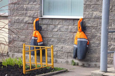 Two overalls hung under the window of a residential building, spring work in a flower garden. Hobby, green thumb, gardening conceptの写真素材
