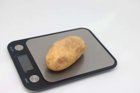 Fresh natural potatoes on electronic kitchen scales. Raw materials for making potato chips. Diet, calorie counting, proper nutritionの写真素材