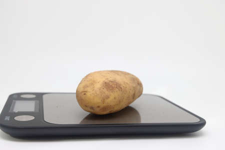Fresh natural potatoes on electronic kitchen scales. Raw materials for making potato chips. Diet, calorie counting, proper nutritionの写真素材