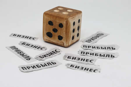 Newspaper clippings with the words business and profit in Russian and a dice, Cyrillicの写真素材