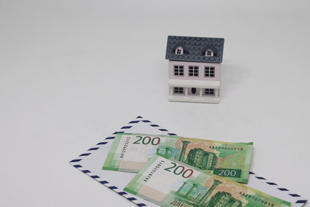 Banknotes in a white envelope and a toy house, funds for the purchase of real estateの写真素材