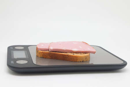 Sliced boiled delicious sausage on electronic scales, calorie counting, proper nutrition