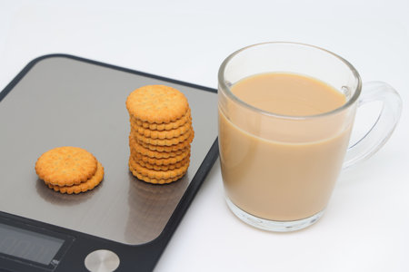 a stack of shortbread cookies with raisins and cinnamon on the white plate and glass of tea on white backgroundの写真素材