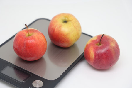 Apples on electronic kitchen scales on a white background, proper nutritionの写真素材