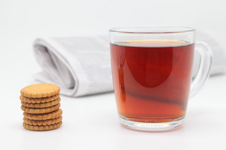 A cup of tea with cookies and a morning newspaper on a white backgroundの写真素材