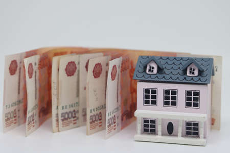 Buying and building a house. house and money. real estate market. house with gray roof on euro banknotes backgroundの写真素材