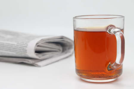 A cup of tea with cookies and a morning newspaper on a white backgroundの写真素材