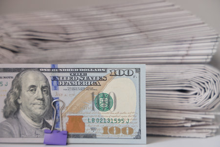 Rolled up stack of newspapers, banknotes stuck between newspapers, news, fake news, corrupt pressの写真素材