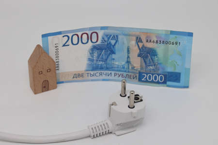 White electric cable and banknotes against the background of a toy model house, expensive...