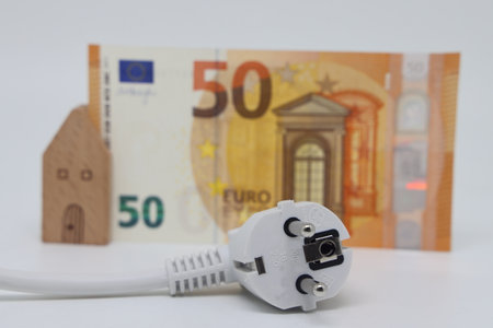 White electric cable and banknotes against the background of a toy model house, expensive electricity, saving electricityの写真素材