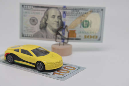 a miniature typewriter stands next to a banknote on a stand. Accurate financial calculation when buying a car. The concept of savings, car loans, gasoline prices and car insurance. Buying and selling a carの写真素材
