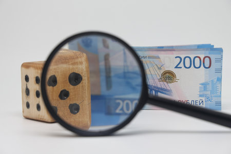 Dice and banknotes through a magnifying glass, profit and revenue unpredictability, plan a marketing strategyの写真素材