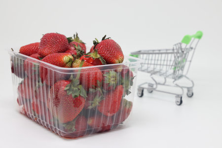 Plastic basket of strawberries on the background of a grocery cart, rising food prices, food crisisの写真素材