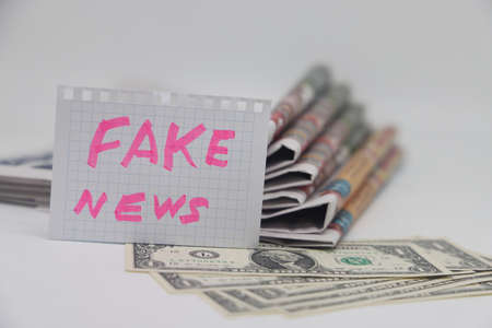 Roll up newspaper with a piece of paper that says fake news, corrupt journalismの写真素材