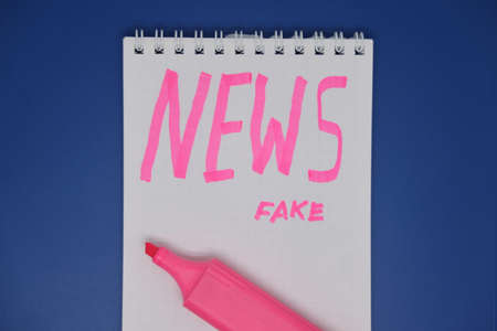 The inscription with a felt tip pen on a piece of paper in a notebook is fake news. Corrupt journalism. fake newsの写真素材