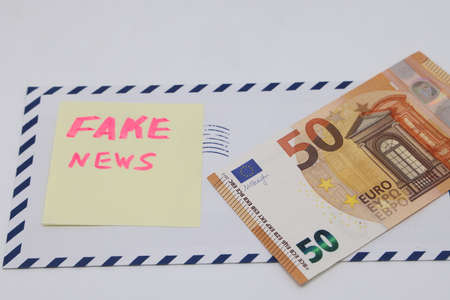 Banknotes on a postal envelope on a light background. Fake news sticker on the envelope. Corrupt...