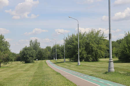 Asphalt paths in an open green landscape park, Kolomenskoye, August 2022